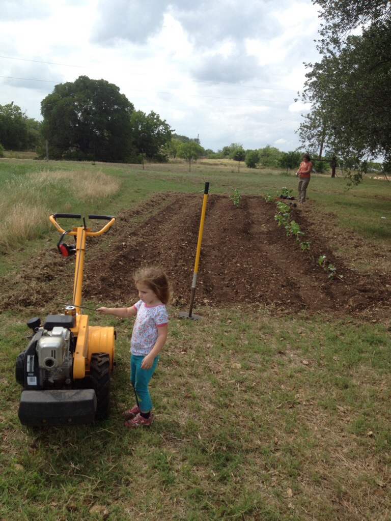 Ele inspects the tiller while taking a break from planting with mom.